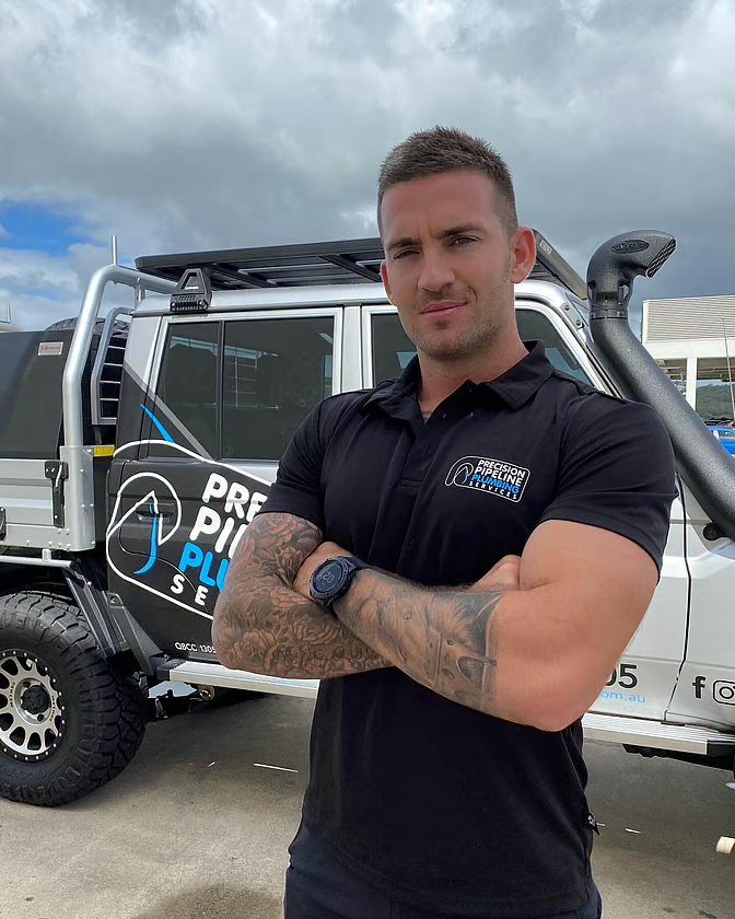 Precision Pipeline plumber standing confidently by a branded work vehicle.