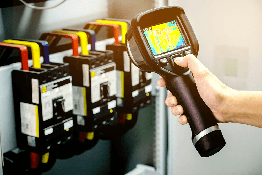 Plumber holding a thermal imaging camera to inspect a wall.